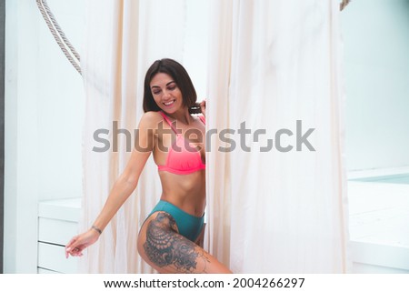 Beautiful tanned fit woman in bikini in backyard posing outdoor by pool
