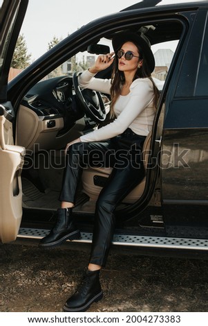 Portrait of a beautiful young woman driving a car. Lady in blackout glasses posing in the car