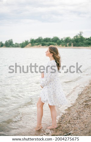 Young beautiful pregnant woman in a beautiful dress near the sea. Picnic. Summer.