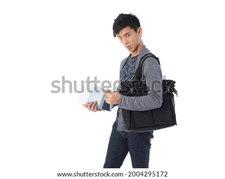 young man wearing gray sweater with black jeans with handbag posing in studio 

