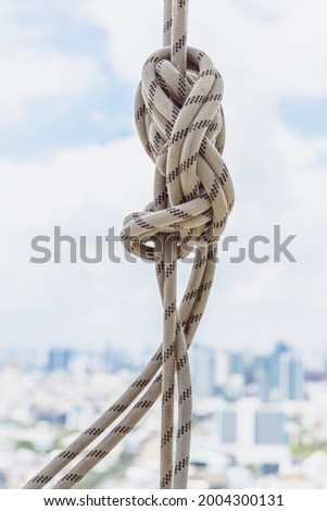 White rope tied on iron bar on building roof.