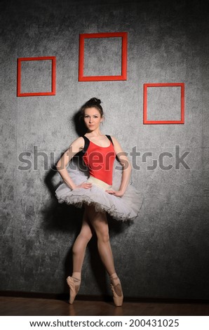 ballet dancer in red and white tutu on wall background with three picture frames