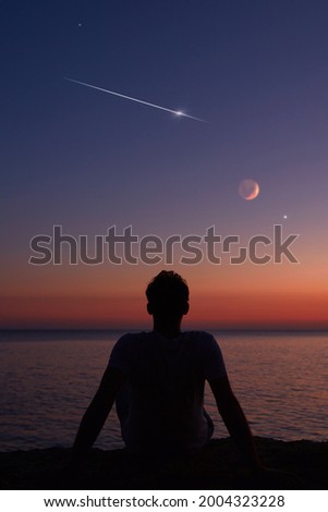 Silhouette of a man looking at the Moon and stars over sea ocean horizon. Royalty-Free Stock Photo #2004323228