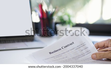 Focus on hand. businessman holding paper of business contract and working at home with computer laptop  