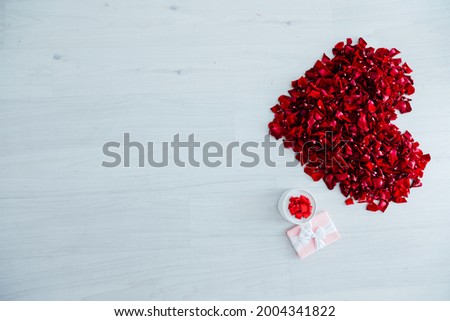 heart of red rose petals gift on white wooden background