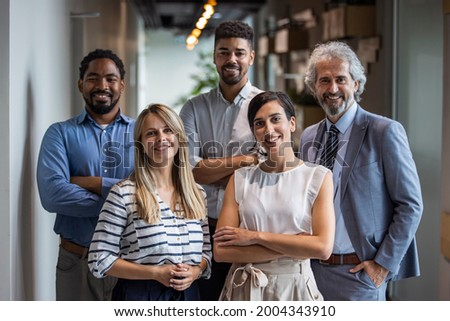 Shot of a group of well-dressed businesspeople standing together. Successful business team smiling teamwork corporate office colleague. Positive multi racial corporate team posing looking at camera Royalty-Free Stock Photo #2004343910