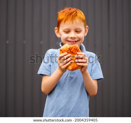 redhead boy eating a bun
