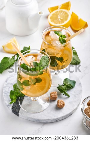 Traditional iced tea with lemon and ice in tall glasses on marble table background Iced tea with lemon. Selective focus. Refreshment cold summer drink.