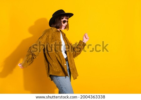 Photo of cute sweet woman dressed cowboy clothes dark spectacles cap smiling dancing empty space isolated yellow color background