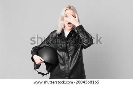 blond pretty woman looking shocked, scared or terrified, covering face with hand. motorbike rider concept