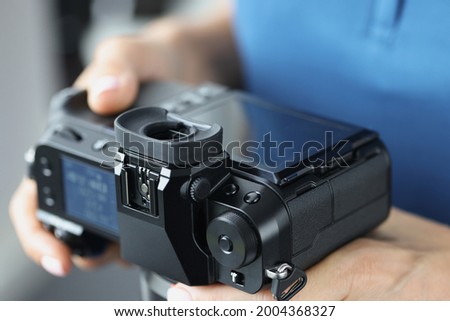 Black professional camera in female hands closeup