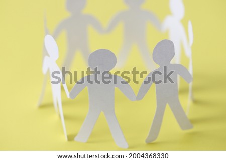 Cut paper people forming union circle on yellow background