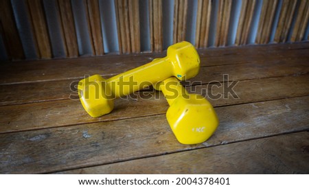 Close up view of pairs of 1 kilogram yellow mini dumbbells on wooden backgrounds. Exercise tool and fitness equipment.