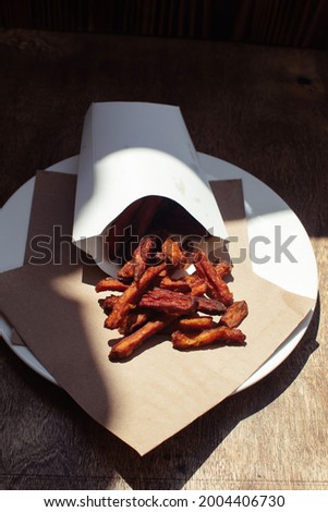 Carrot fries in a cardboard box. Vegetarian fast food dish. Grilled vegetables. BBQ cooking concept for people who do not eat