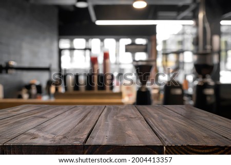 Empty wooden table with blurred background of cafe or coffeeshop. For present product. Royalty-Free Stock Photo #2004413357