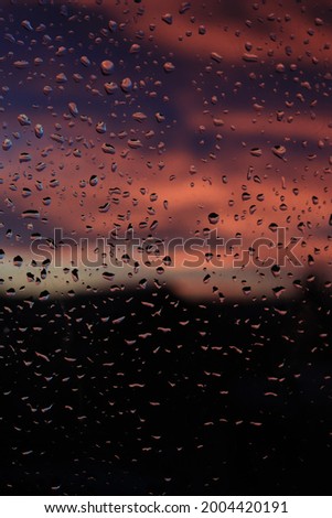 Window after rain. Water drops on the glass. Sunset in village. Nature photography. 