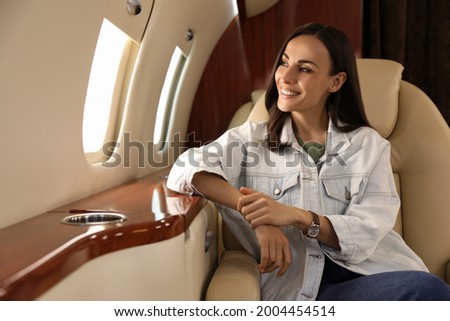 Young woman looking out window in airplane during flight Royalty-Free Stock Photo #2004454514