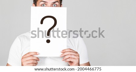 Anonymous man, peeking behind of interrogation symbol. Male incognita. Man a question, anonymous, incognita. Man holding Question Mark. Question mark, symbol. Royalty-Free Stock Photo #2004466775