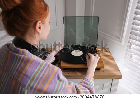 Beautiful young woman using turntable at home Royalty-Free Stock Photo #2004478670