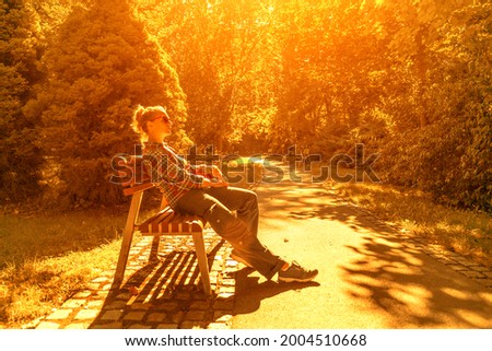 Enjoy nature. Relaxed state, contemplation of the landscape. A woman is sitting on a park bench. Peace and beauty.