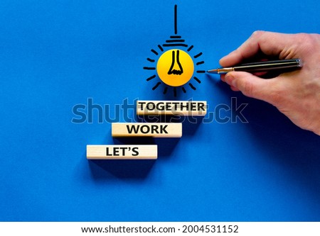 Work together symbol. Wooden blocks with words Let is work together on beautiful blue background. Businessman hand, light bulb icon. Business, let is work together concept. Copy space.
