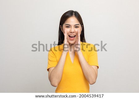 Excited asian woman shout out loud wow with hands on isolated background. Happy shocked face female wow promotion advertising concept. Joyful teenage girl in yellow shirt standing in white room.