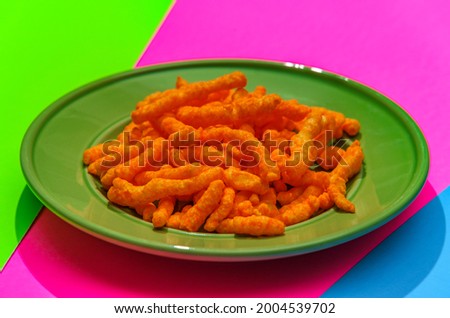Cheese puff unhealthy junk food snack on stylized modern neon colored background