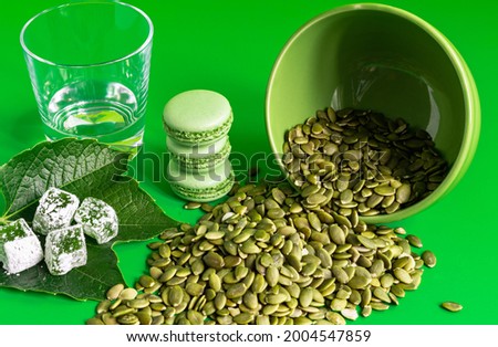 green Turkish delight and Macarons and pumpkin seeds on green background