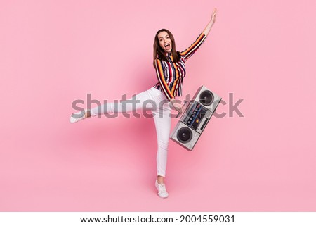 Photo of impressed funky young lady wear striped shirt dancing holding boom box smiling isolated pink color background