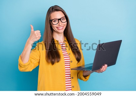 Photo of young attractive pretty girl happy positive smile hold laptop show thumb-up like fine isolated over blue color background