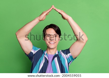 Photo of cool brunet young guy hands up wear striped shirt isolated on green color background