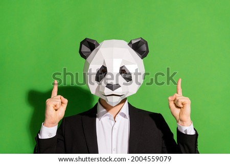 Photo of wacky hipster guy indicate fingers up empty space wear panda mask black tuxedo isolated on green color background