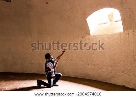 man with arms raised towards a window light , inspiration concept