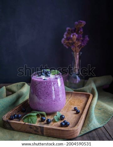 Blueberry smoothie on a wooden salver and black background .  Bilberry smoothie low key . Whortleberry smoothie on a green napkin and wooden table. 