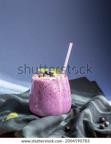 Blueberry smoothie on a wooden salver and blue background with a copy space .  Bilberry smoothie low key . Whortleberry smoothie on a green napkin and wooden table.  Royalty-Free Stock Photo #2004590783