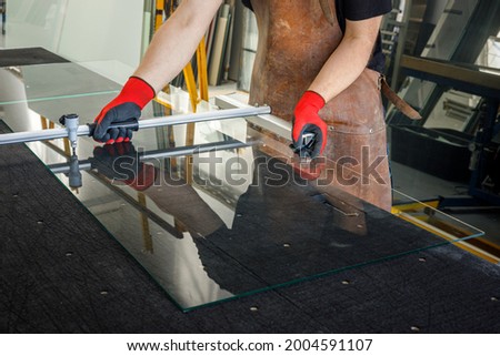 The glazier cuts a large sheet of glass. Glass workshop, Specialist work tools  Royalty-Free Stock Photo #2004591107