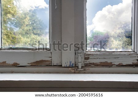 Old wooden window frames with rotting wood and cracked peeling paint, house needs renovation and new frames closeup Royalty-Free Stock Photo #2004595616