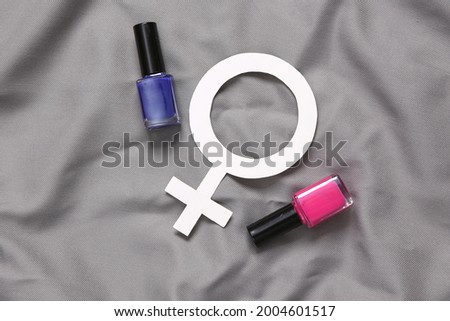 Bottles of nail polish and venus symbol on gray silk background. Top view