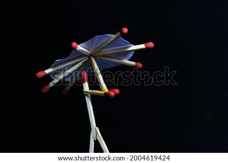 A matchstick man with a matchstick umbrella in the rain. Raining concept. Matchstick art photography used matchsticks to create the character. Royalty-Free Stock Photo #2004619424
