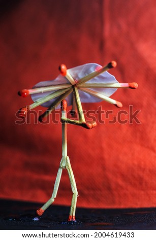 A matchstick man with a matchstick umbrella in the rain. Raining concept. Matchstick art photography used matchsticks to create the character. Royalty-Free Stock Photo #2004619433