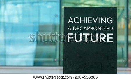 Achieving a decarbonised future  on a city-center sign in front of a modern office building	
 Royalty-Free Stock Photo #2004658883