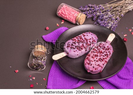 Lavender flavored ice cream. Flower bouquet, pink sugar, rose petals. Black stone concrete background, copy space