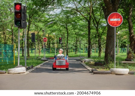 Safety traffic playground. Driving school kids education road rules. Small boy driving toy car stops at traffic lights on playground child learn traffic rules game road safety education children area