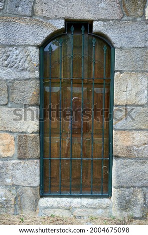 Self-portrait of a photographer reflected in a window pane with wrought iron grille