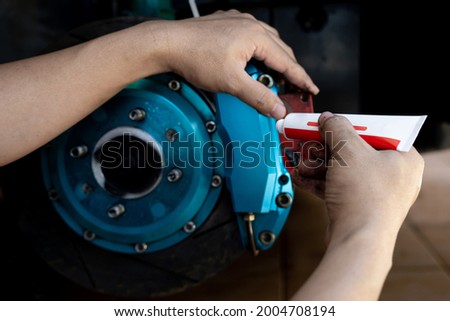 Disk brake service concept : Close up hand a man use Grease Anti-seize to brake pad and cleaning system in service shop Royalty-Free Stock Photo #2004708194