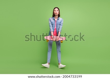 Full body photo of funny brunette hair millennial lady hold skate wear jeans jacket isolated on green color background