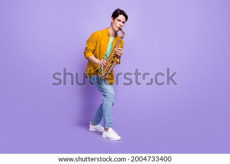 Full length photo of young man happy positive smile play sax jazz artist isolated over violet color background Royalty-Free Stock Photo #2004733400