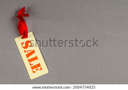 Rectangular sale tag on gray background. Paper tag with red ribbon. Concept for sales promotion. Sale. Copy space.
