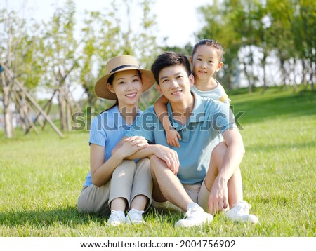 Happy family of three sitting on the grass high quality photo