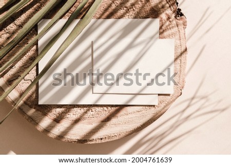 Two blank cards on wooden background with palm leaves shadows. Minimal concept mock up background. Top view.